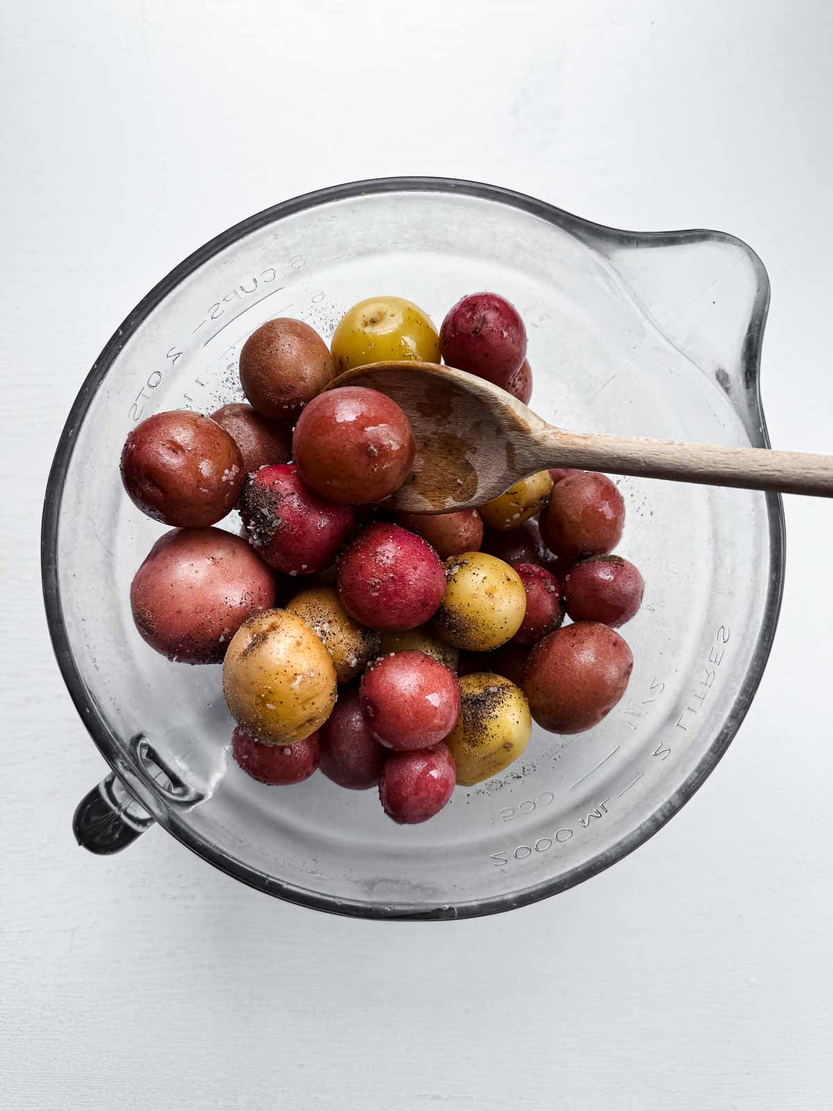 wooden bowl with microwaved potatoes with wooden spoon.