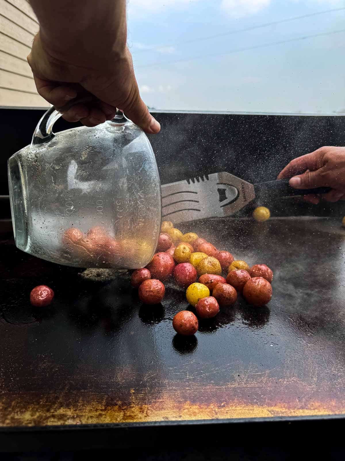 pouring the microwaved potatoes to the flattop griddle.