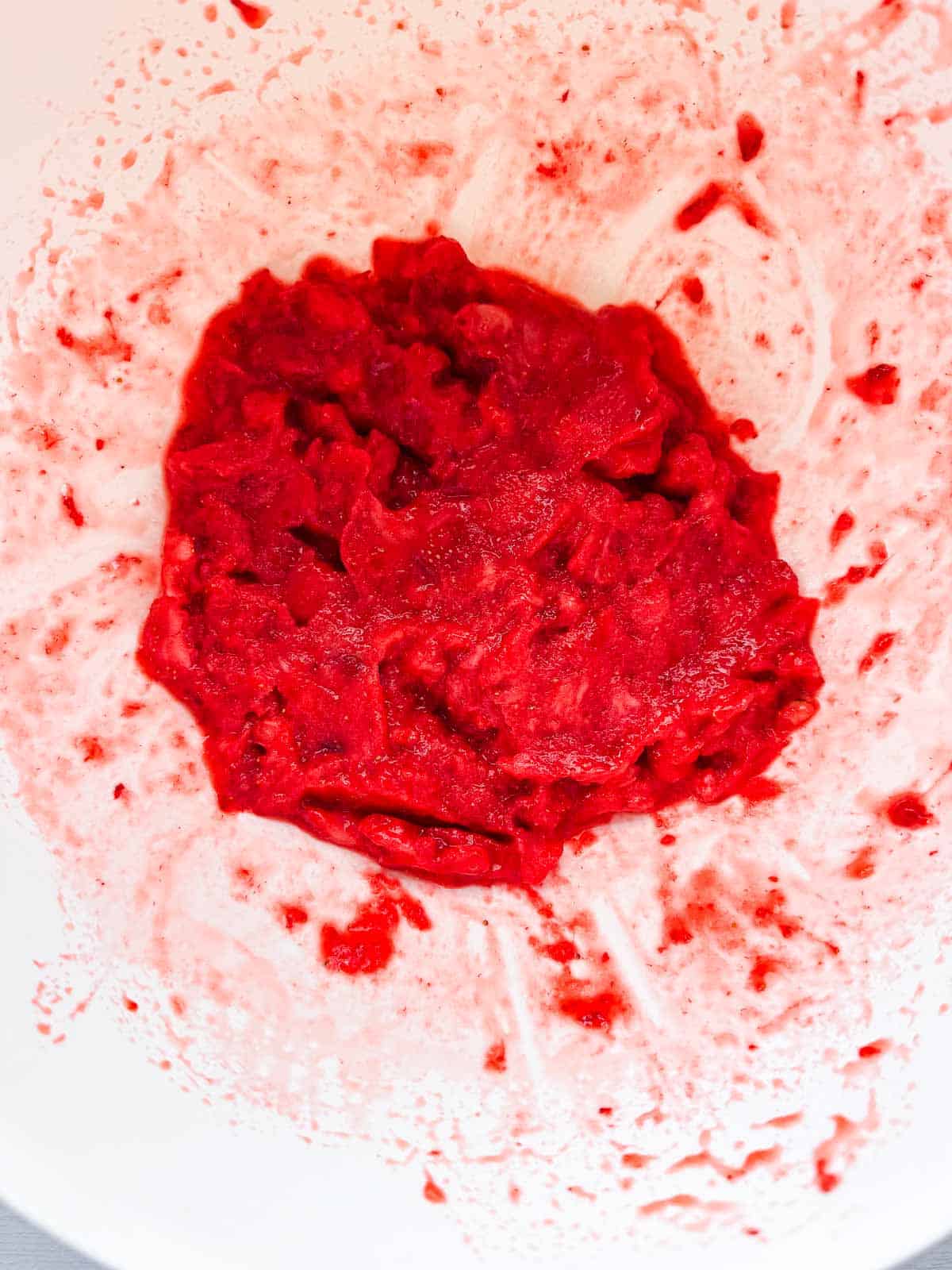 big white bowl of crushed strawberries.