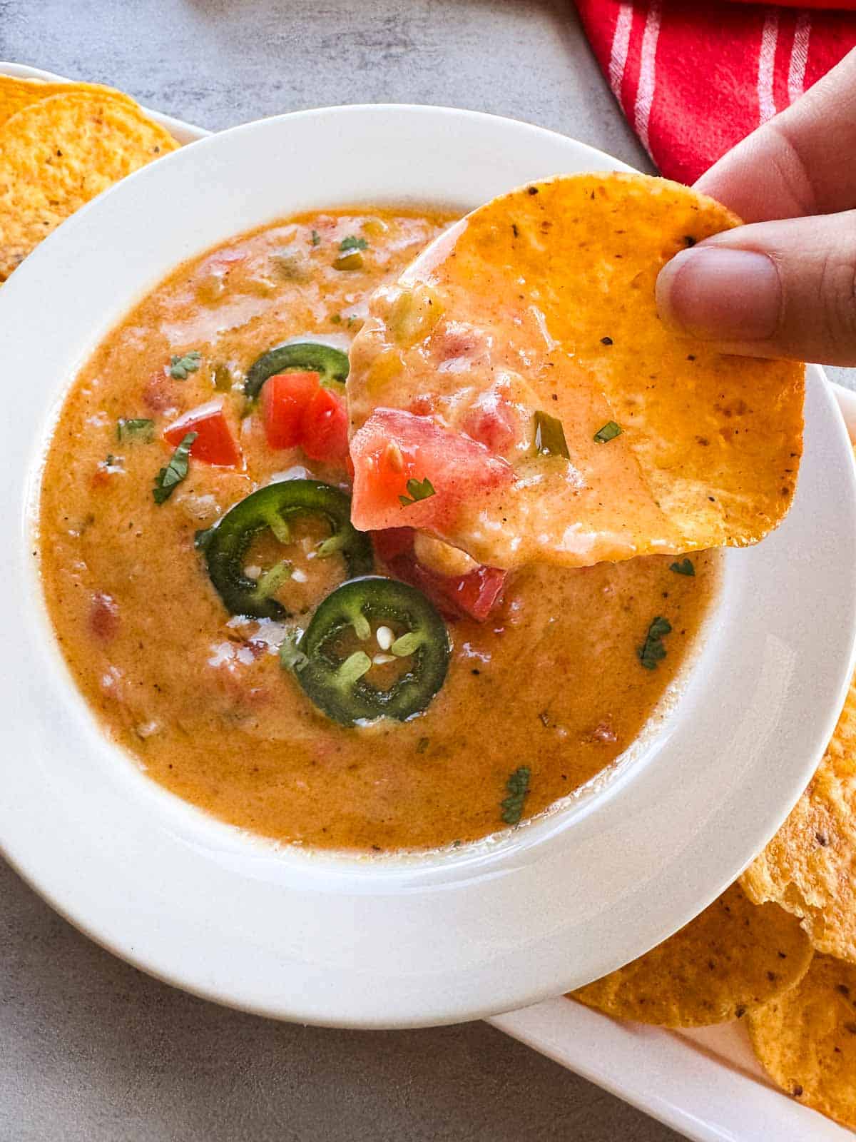 a yellow corn tortilla chip dipped into a bowl of queso.