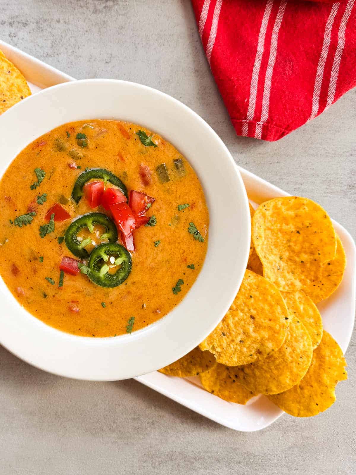 white bowl of queso with tortilla chips.