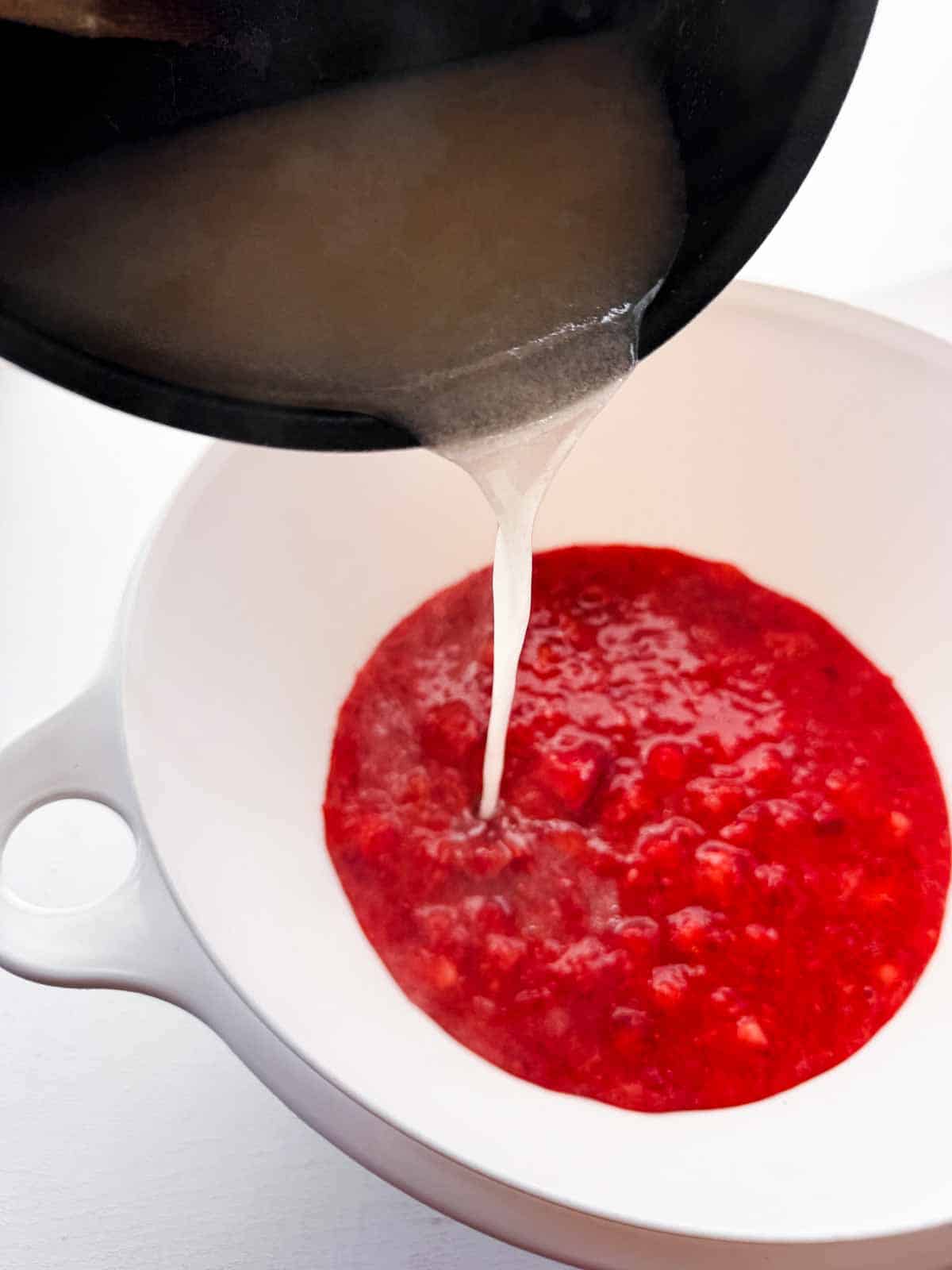 pouring the sure-jell liquid into the crushed berry bowl.