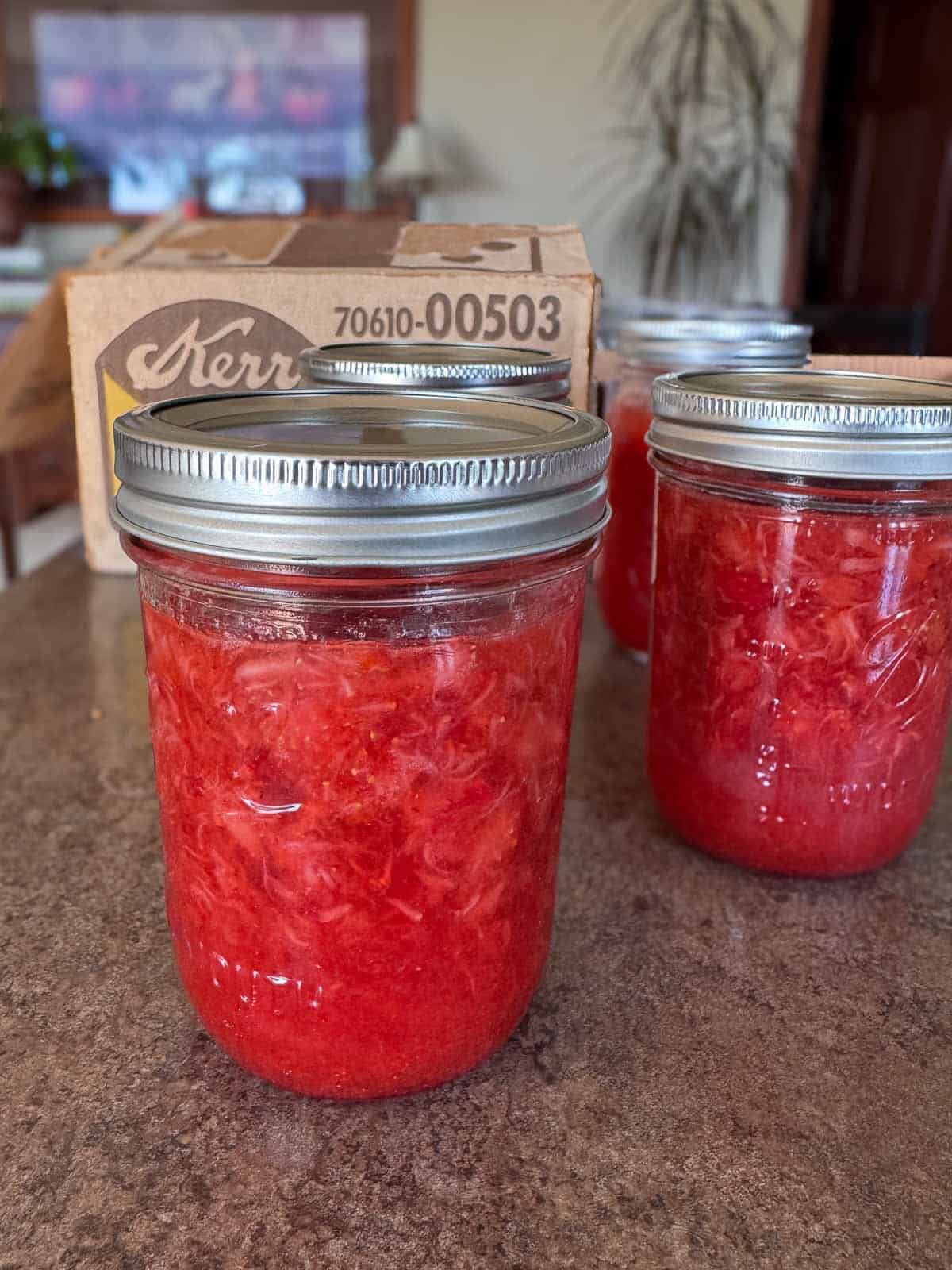 three jars of strawberry jam sitting on the countertop in my kitchen.