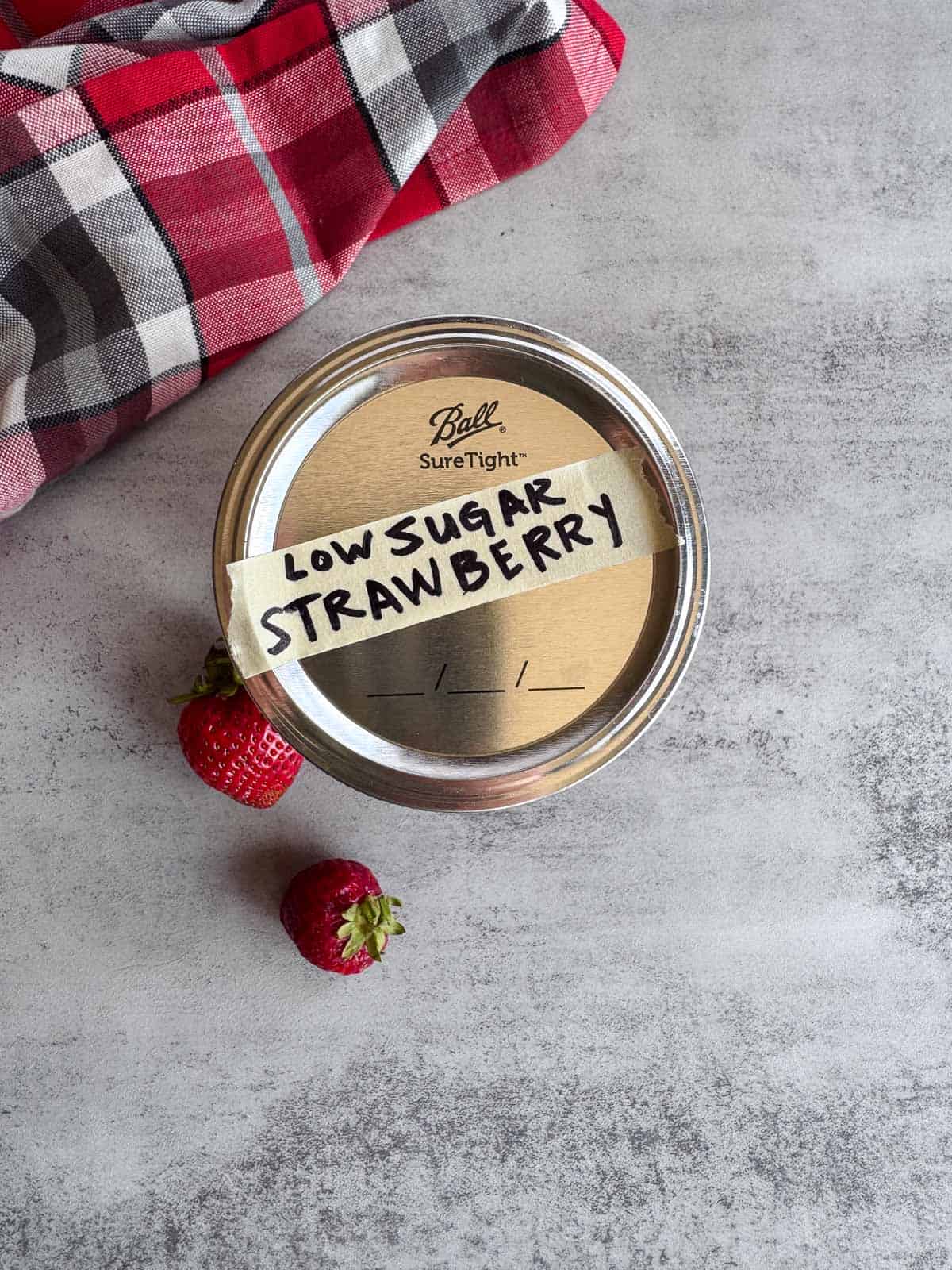 top of a strawberry jam jar with a label with low sugar strawberry jam.