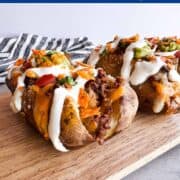 Two baked potatoes stuffed with taco-seasoned ground beef, melted cheese, crushed chips, guacamole, and sour cream, served on a wooden board. Text overlay reads "Taco Potatoes – Gluten Free | Low FODMAP" with the URL loveablelemons.com.
