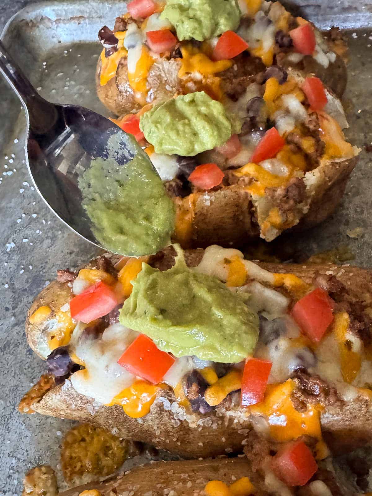 a spoonful of guac on top of stuffed baked potatoes.