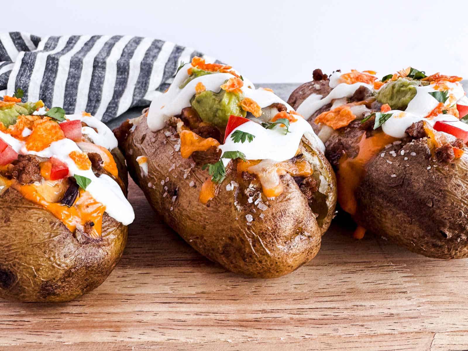 three stuffed baked potatoes with taco fillings.