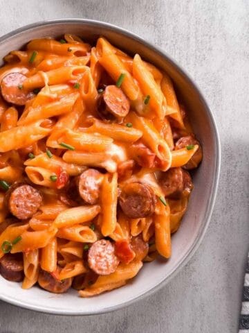 bowl of cheesy, penne pasta with sliced turkey brats in a tomato based sauce.