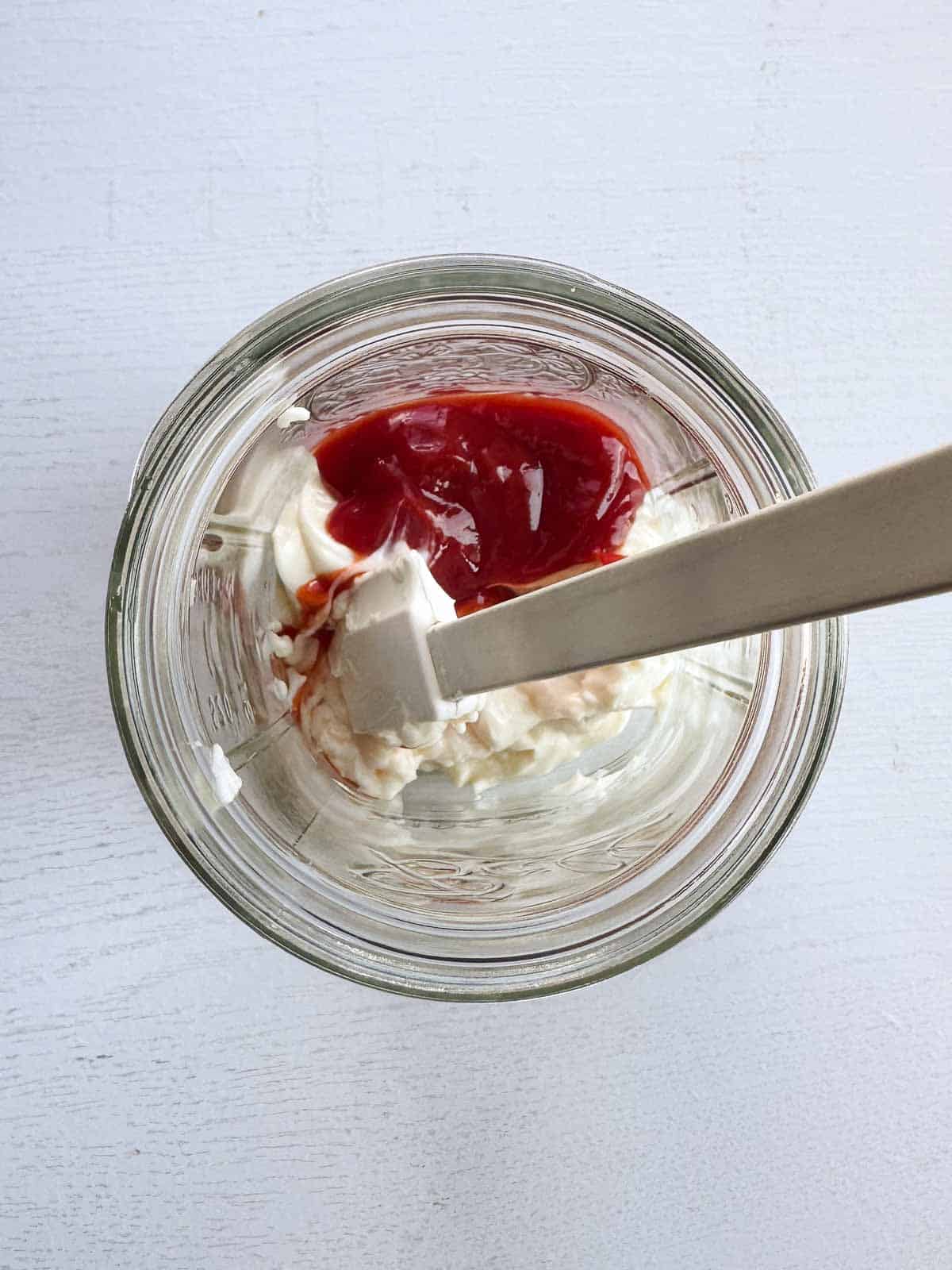 mayo and ketchup in a wide mouth mason jar with a spatula.