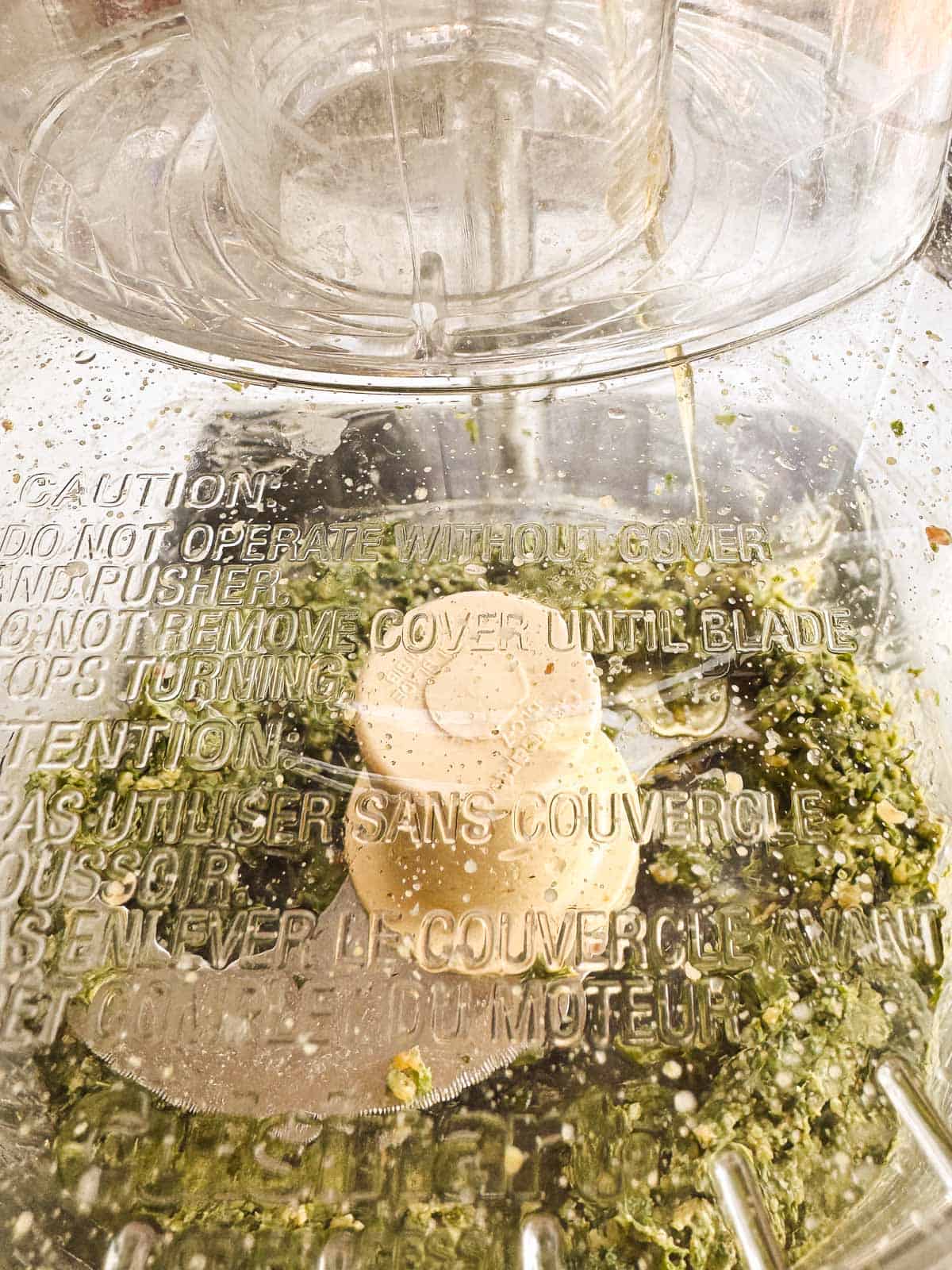 food processor running with a stream of oil running inside.