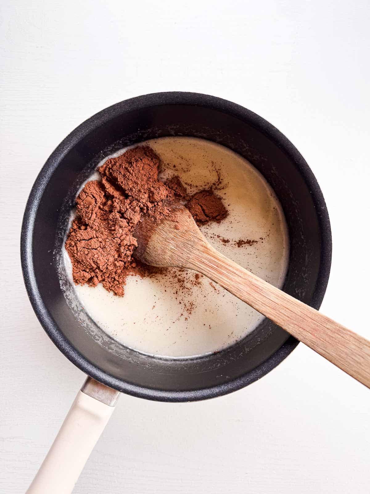 cocoa powder added to the saucepan with a wooden spoon.