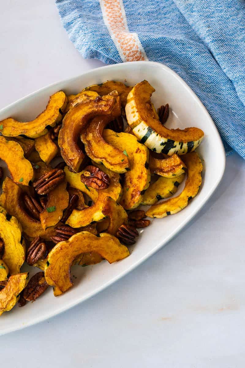 close up of roasted delicata squash on a white platter.
