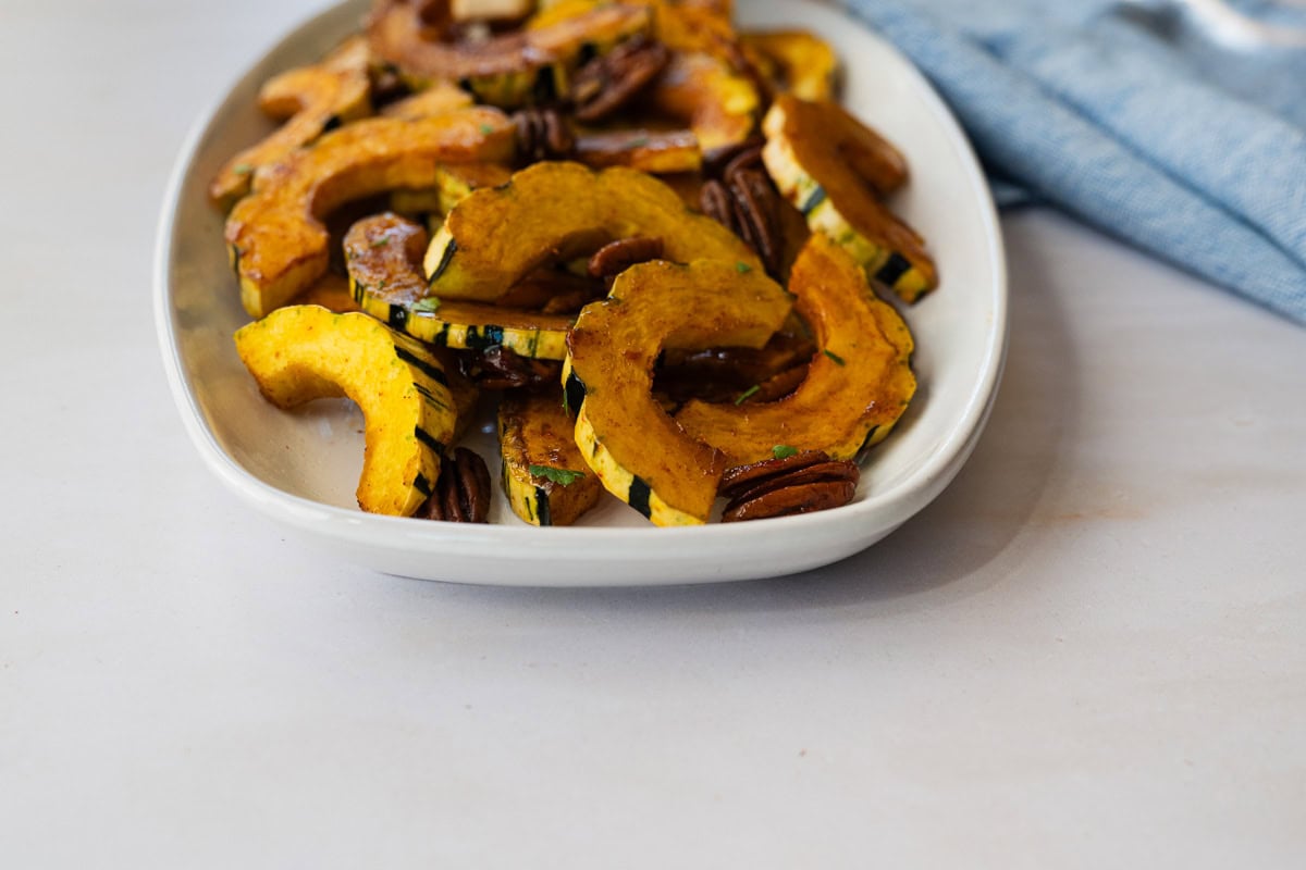 close up of roasted delicata squash on a white platter.