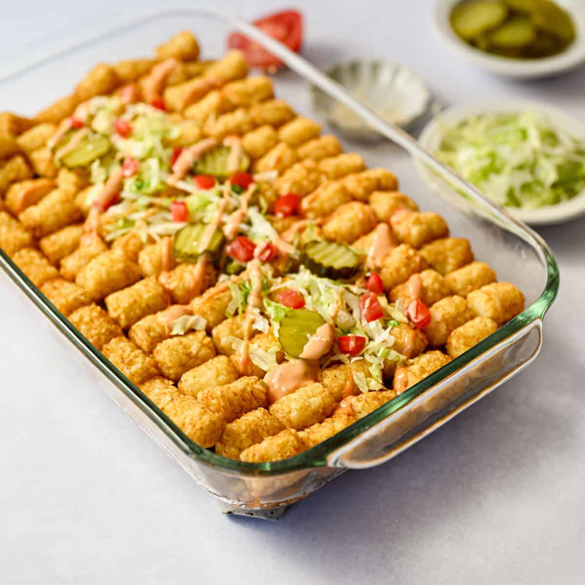 baked tater tot casserole topped with shredded lettuce, tomatoes, pickles and more thousand island dressing.
