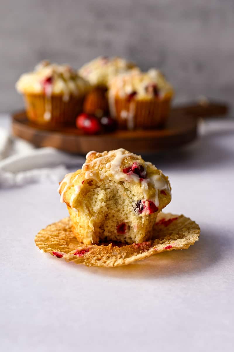 bite missing from a cranberry orange muffin on an open muffin paper liner.