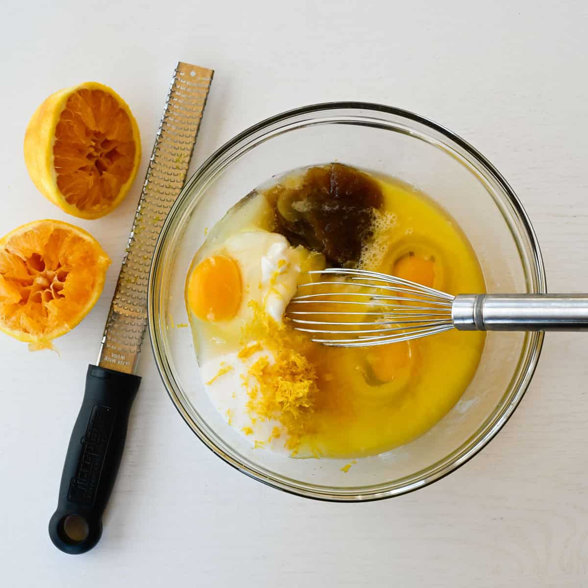 wet ingredients for the muffins alongside squeezed orang halves and a microplane.