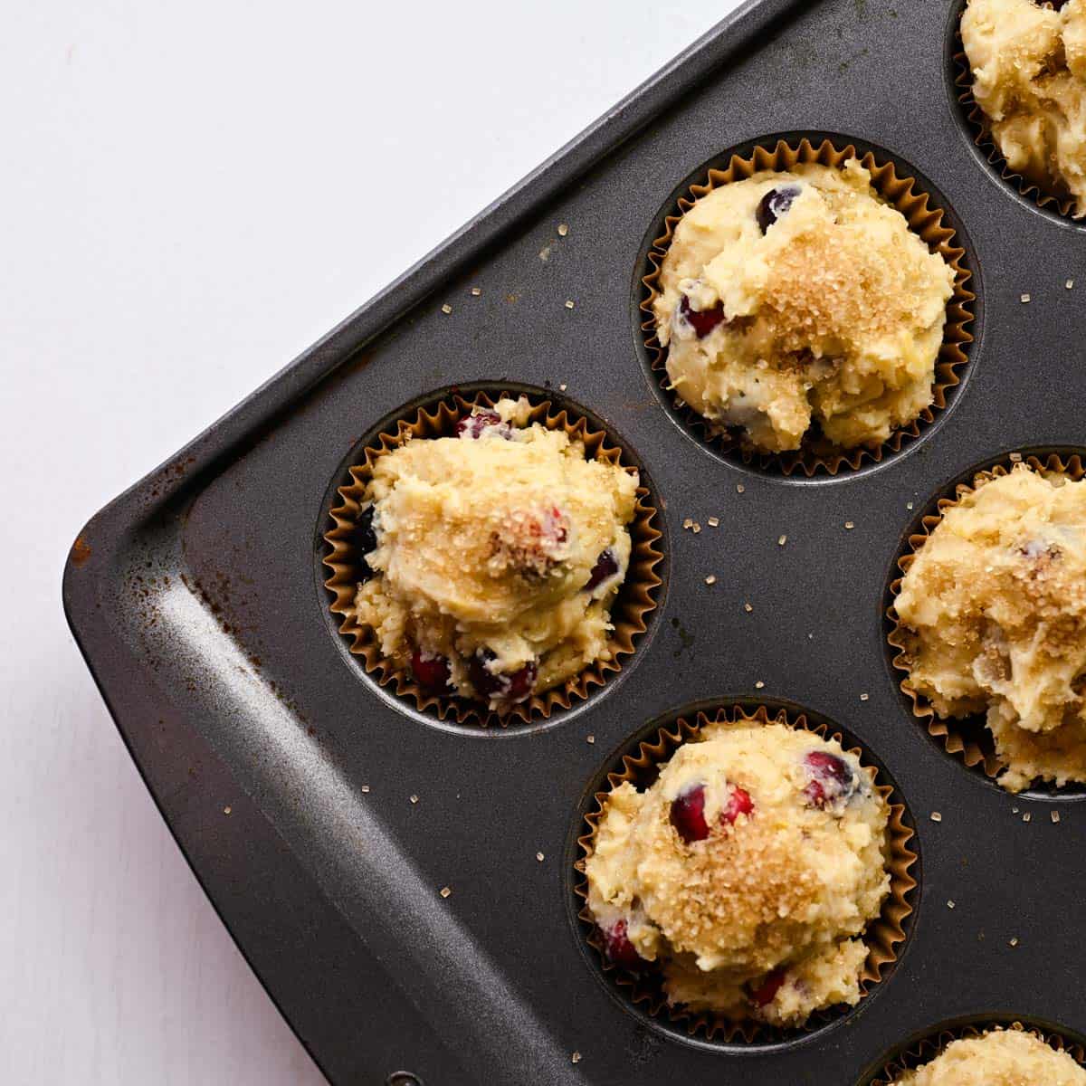 muffin tin filled with batter and topped with turbinado sugar.