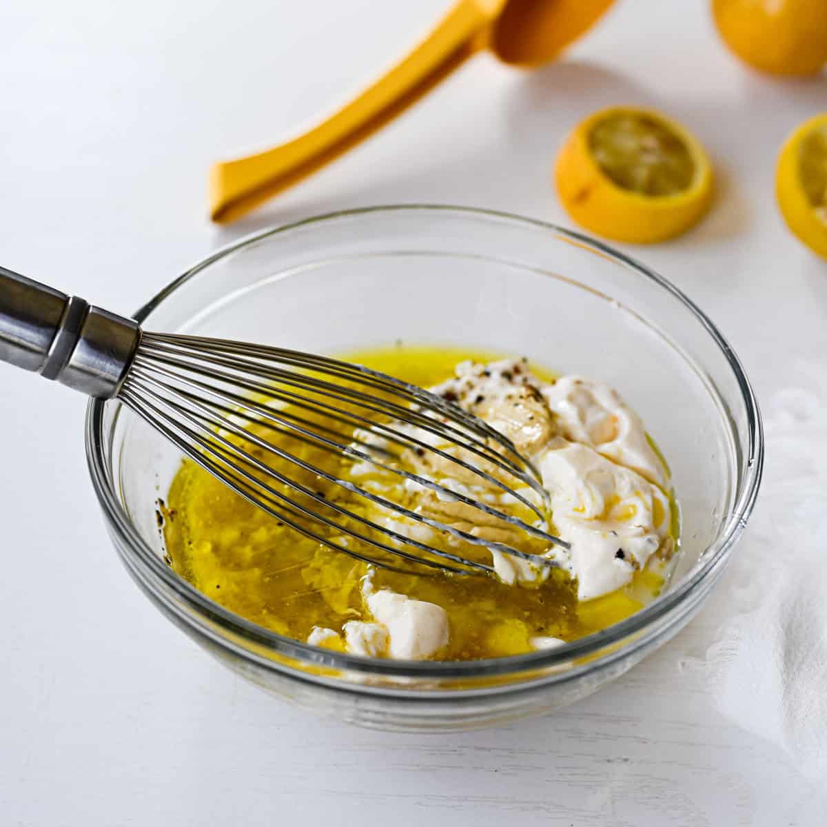 glass bowl with the base ingredients for caesar dressing.