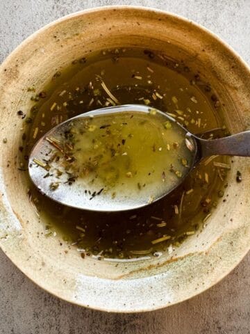 ceramic bowl of salad dressing with a spoon.
