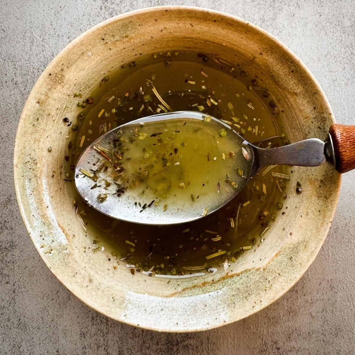 ceramic bowl of salad dressing with a spoon. 
