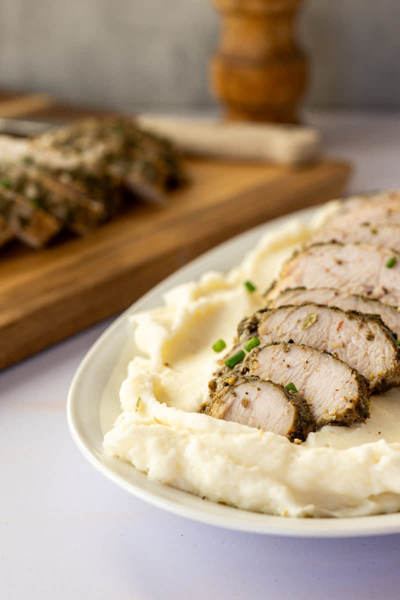 sliced turkey tenderloin on a bed of mashed potatoes. 