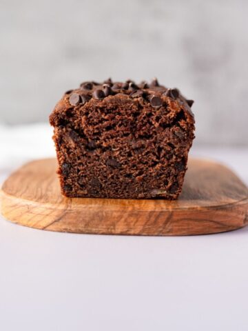a loaf of chocolate banana bread on a wooden cutting board.