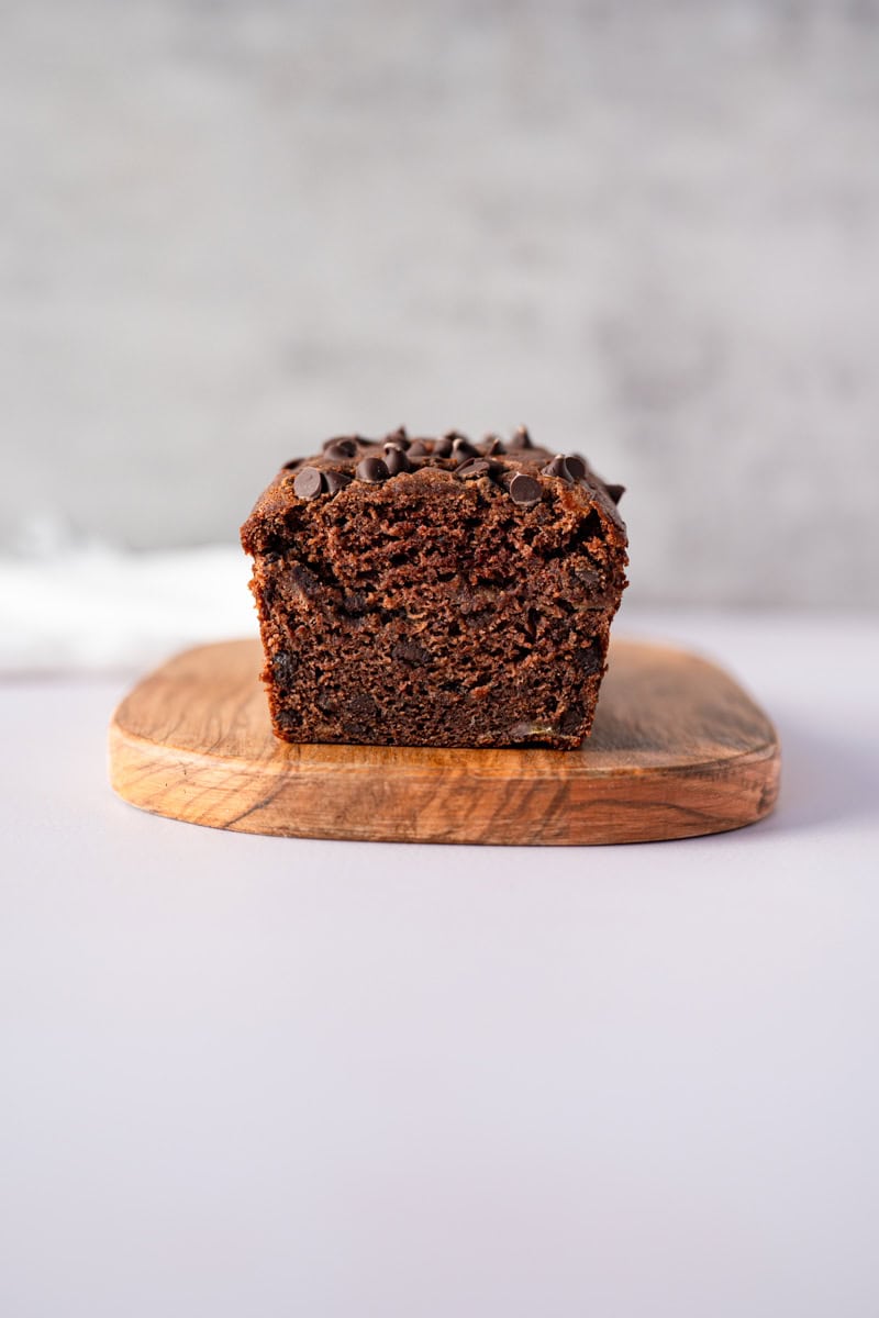 a mini chocolate banana bread loaf on a wooden cutting board.
