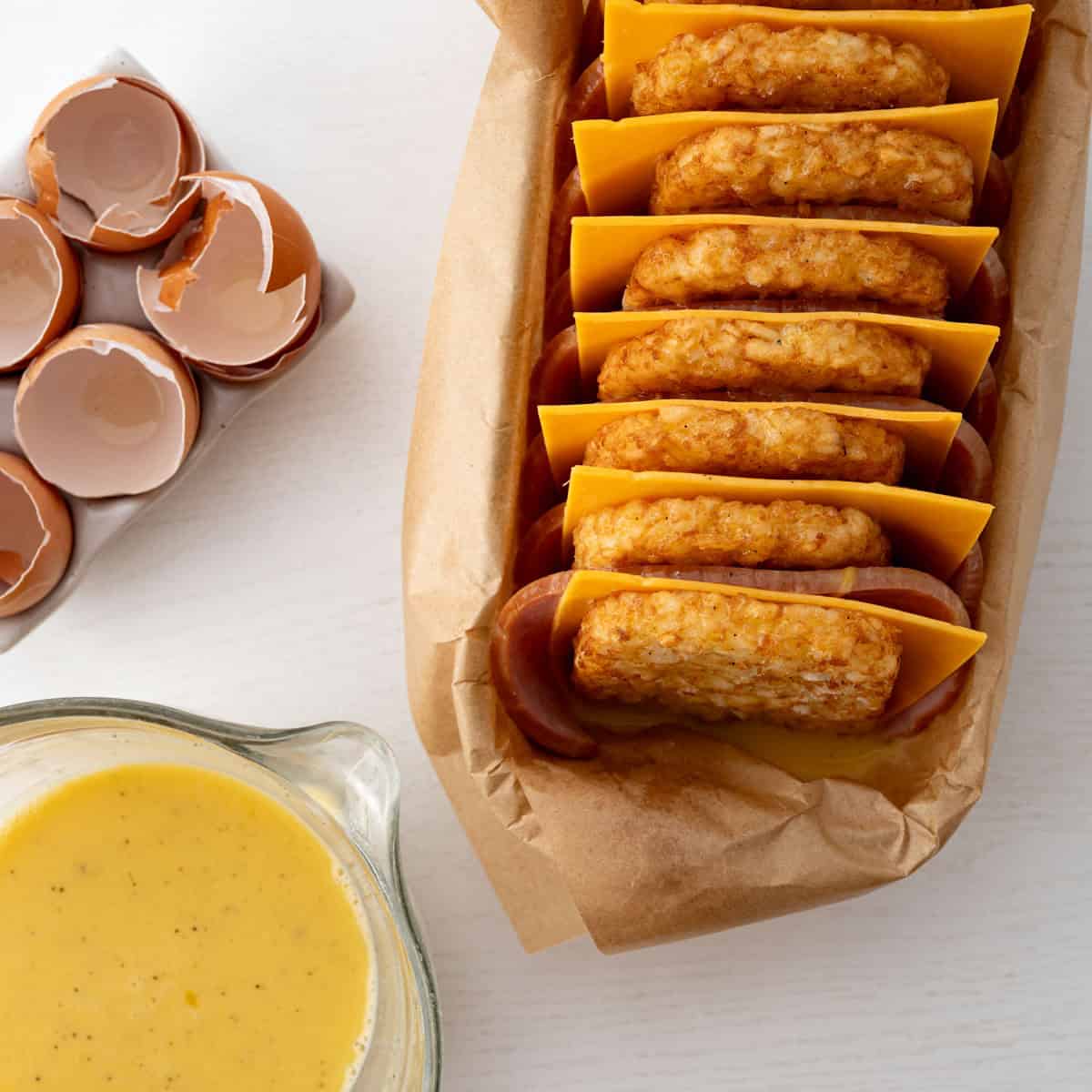 loaf pan with layered hash brown patties, whisked egg mixture and cracked eggs.