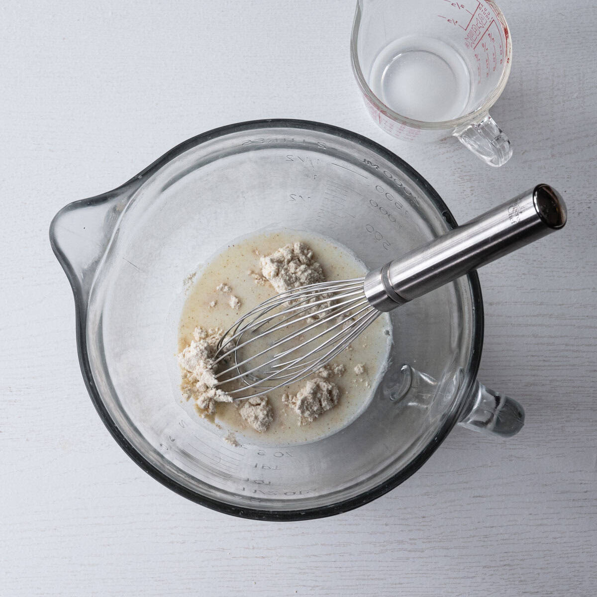 inside a glass bowl, milk, masa harina corn flour and whisk.