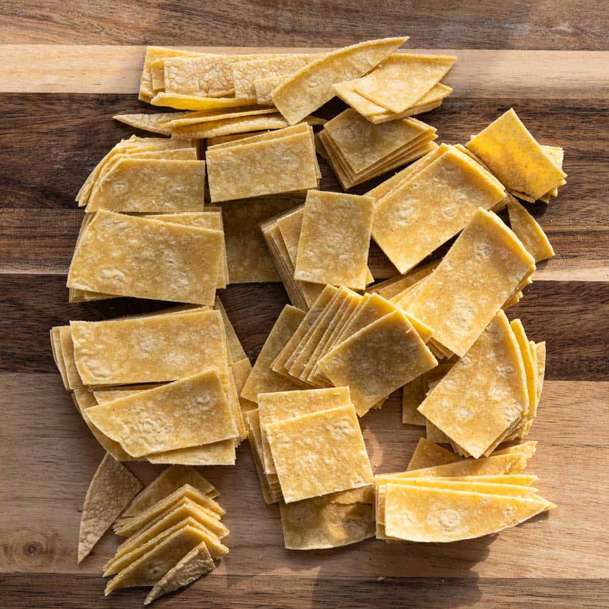 cut up corn trotillas on a wooden cutting board.
