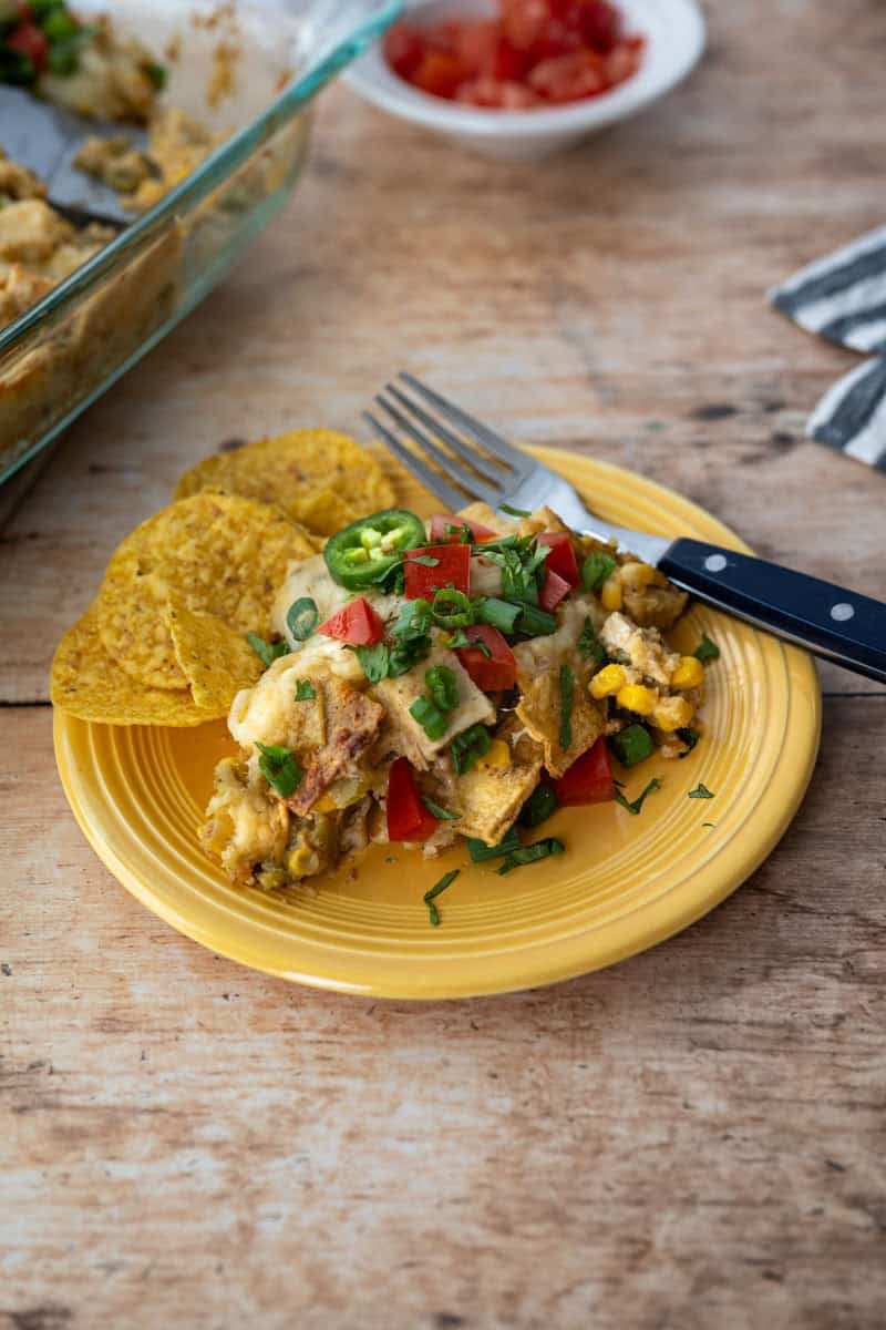 a spoonful of chicken casserole with a fork and a handful of tortilla chips.