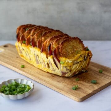 hash brown patty casserole removed from the parchment paper sittong on a wooden cutting board.