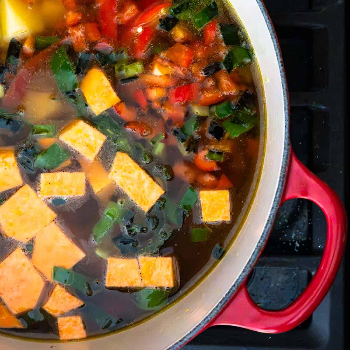 diced vegetables in a red dutch oven on the stove top.
