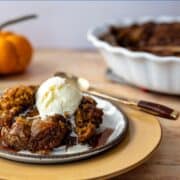 pumpkin pudding cake with pecans and melting ice cream on a plate.