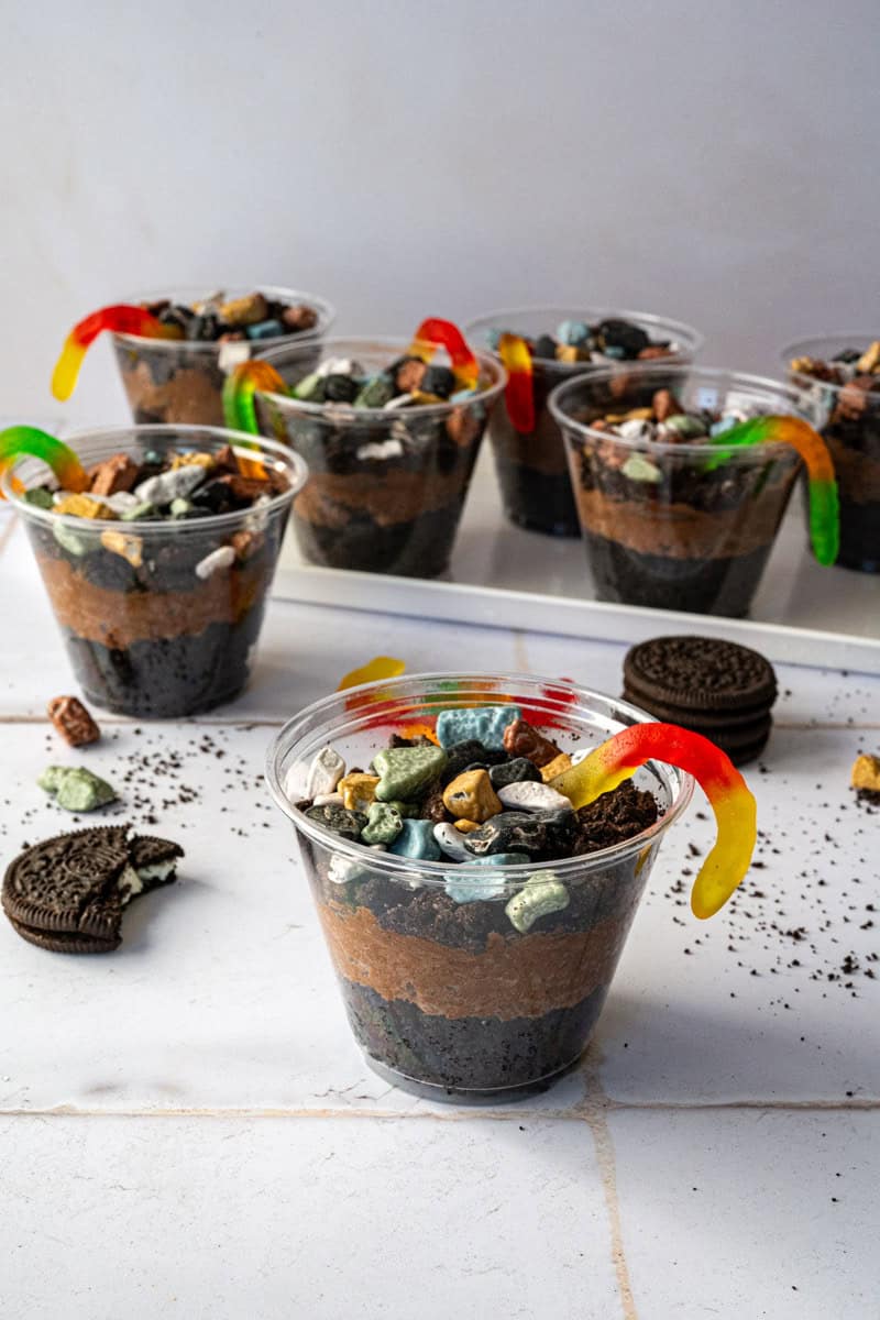 filled dirt cake cups with layers of brownies, chocolate mousse, oreos, candy rocks and gummy worms.