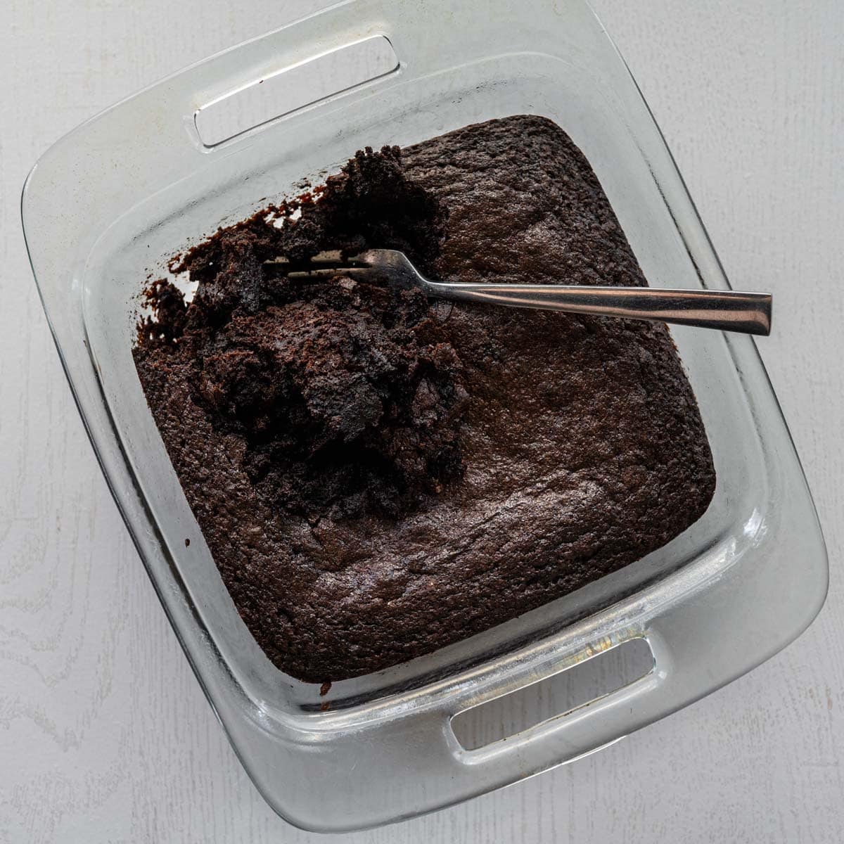baked brownies in a baking pan crumbling with a fork.