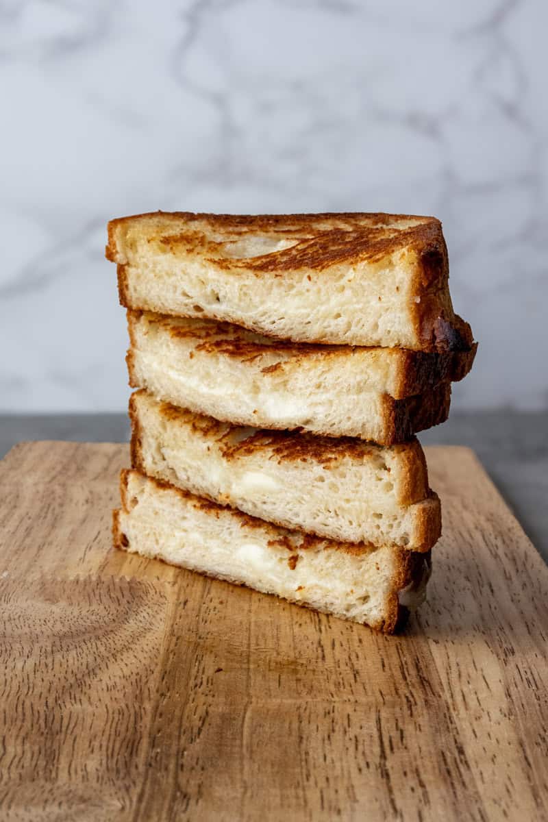 stacked havarti grilled cheese on a wooden board.