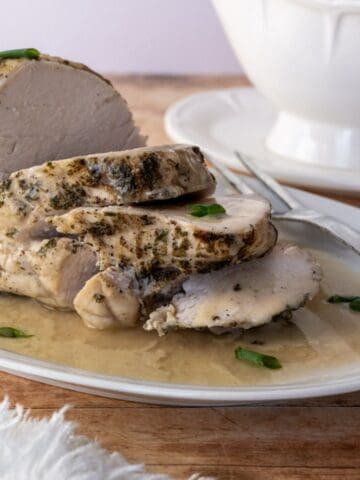 sliced turkey breast on a white platter with gravy.