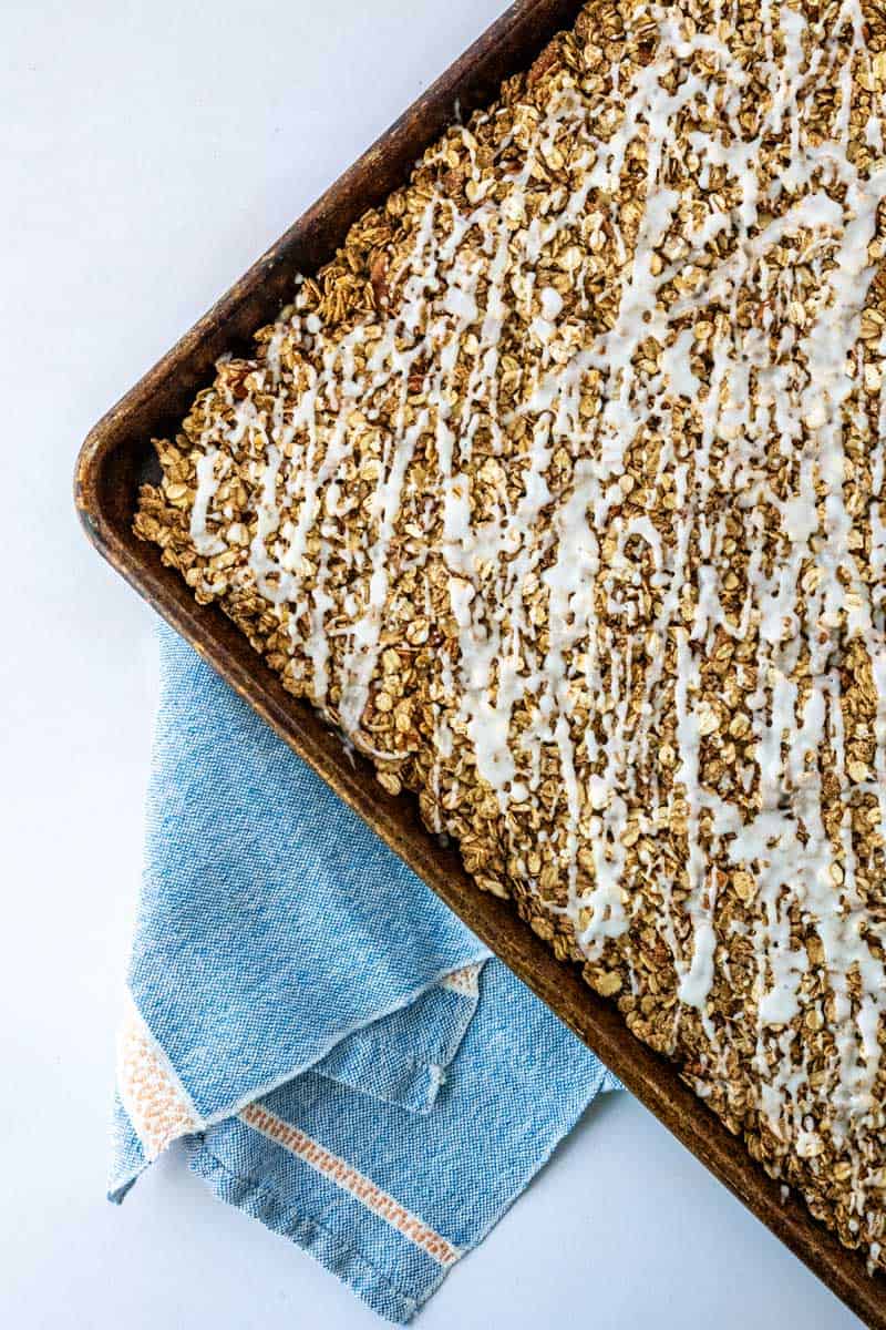 baked cinnamon roll granola drizzled with glaze in the pan before breaking into clusters.