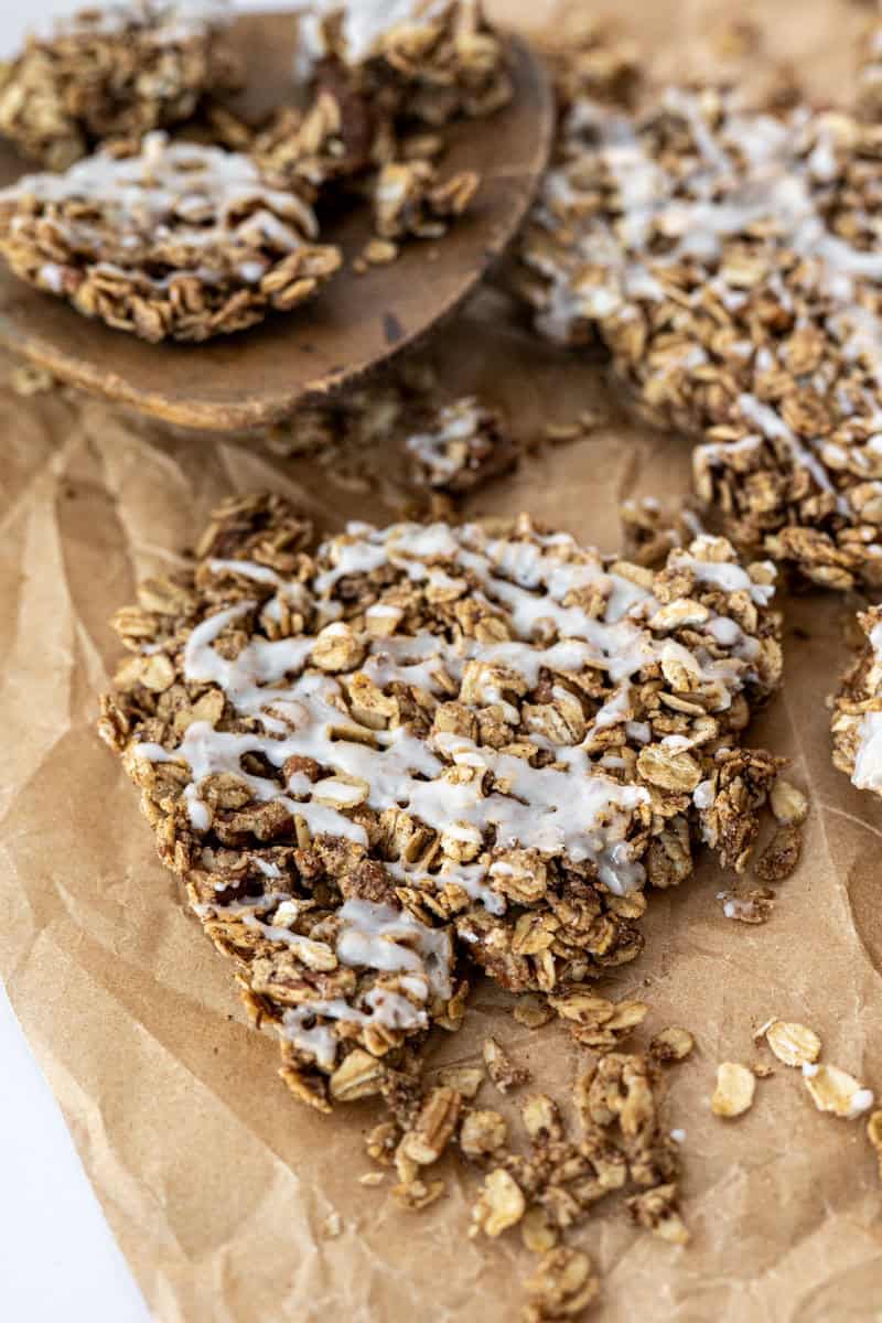 multiple clusters of cinnamon roll granola on a piece of parchement paper. 