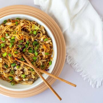 bowl full of chow mein noodles with chop sticks.