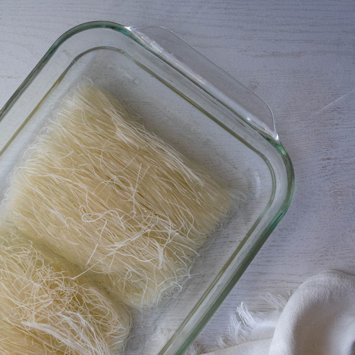 thin rice noodles soaking in a glass baking dish.