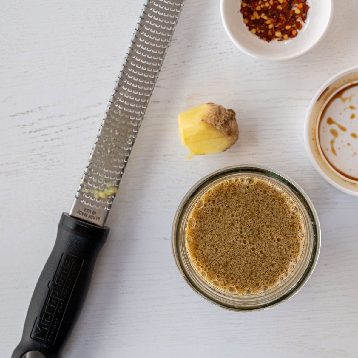freshly grated ginger alongside a microplane and a wide mason jar.