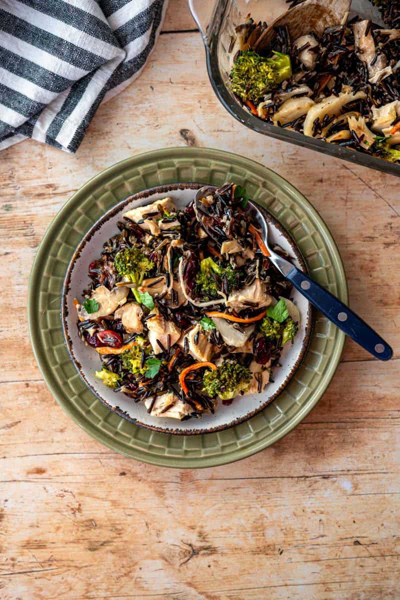 plate full of wild rice turkey casserole next to a baking dish. 