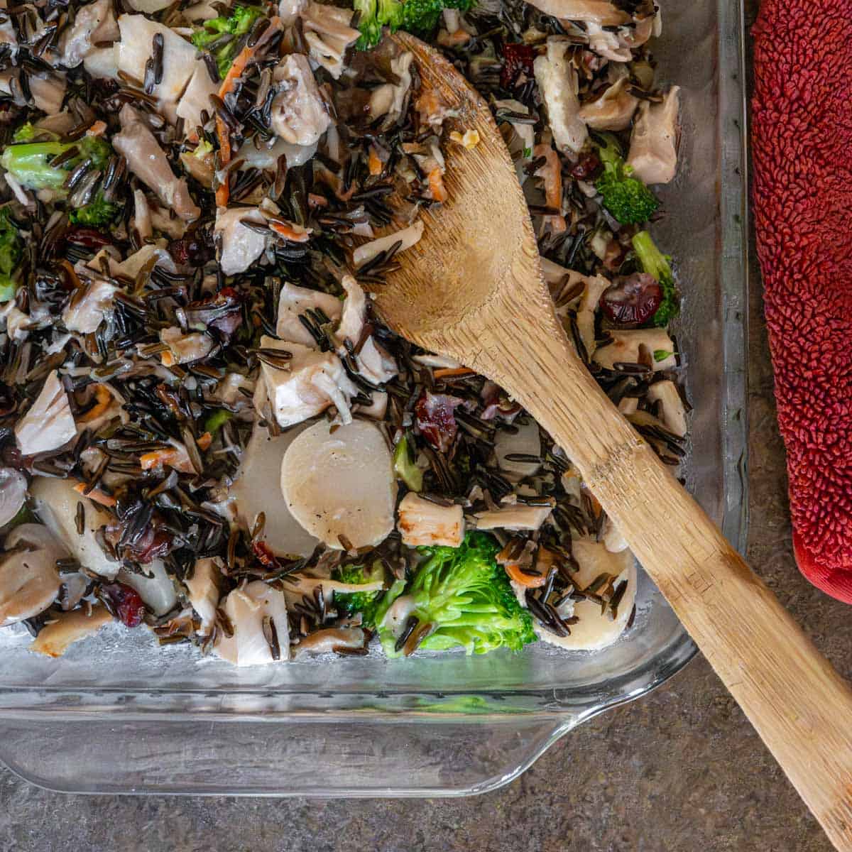 casserole in a 9x13-inch glass baking dish with a wooden spoon.