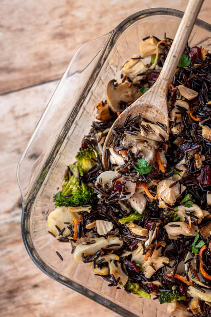 glass baking dish with baked casserole with a wooden spoon.