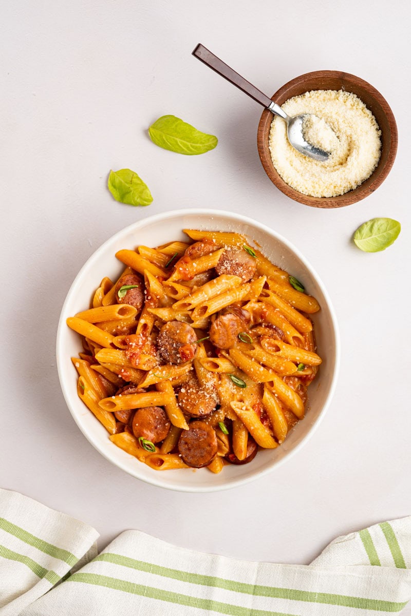 overhead shot of the cooked pasta in a bowl with a small bowl of parmesan cheese with a small spoon.