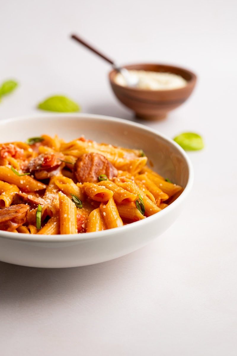 bowl of kielbasa pasta topped with grated parmesan cheese. 