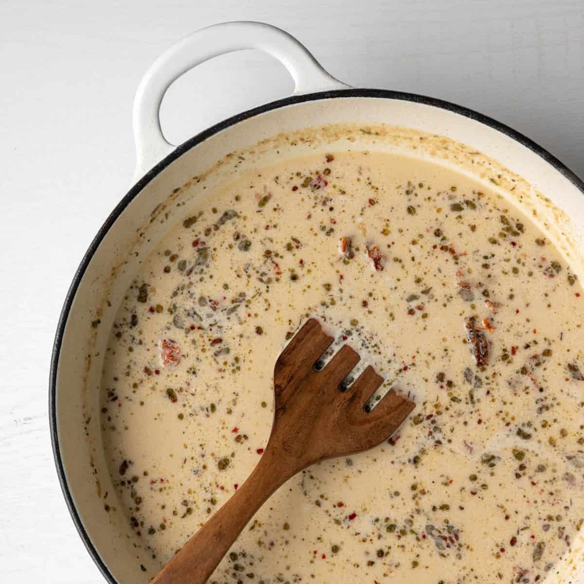 the dairy free sauce ingredients in the pan without the chicken and a wooden spoon.
