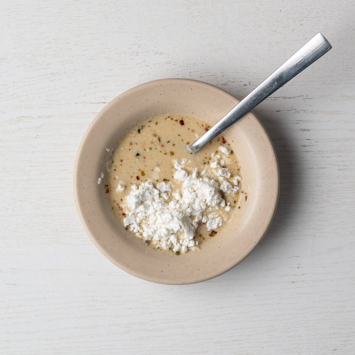 small bowl of sauce and cornstarch with a spoon.